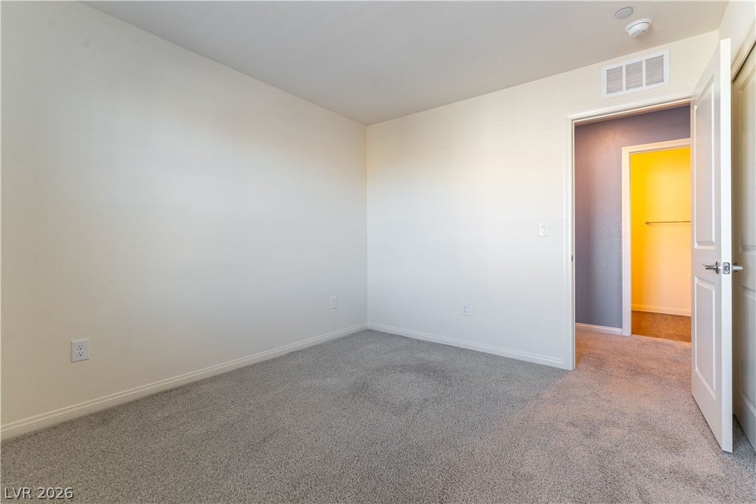 6911 Orange Horizon Street, North Las Vegas, NV 89086 Neutral walls and plush carpeting anchor this versatile bedroom workspace or sleeping area.