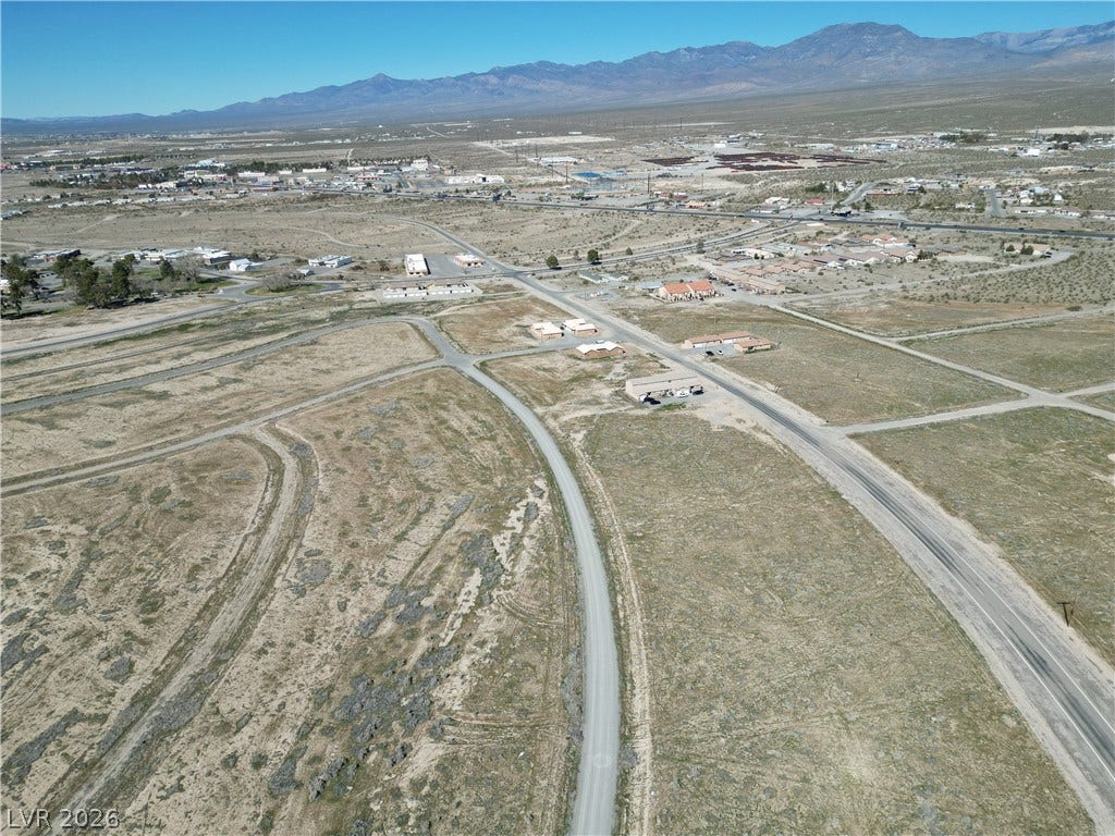 Expansive desert terrain rolls toward majestic mountain ridges under clear blue skies.
