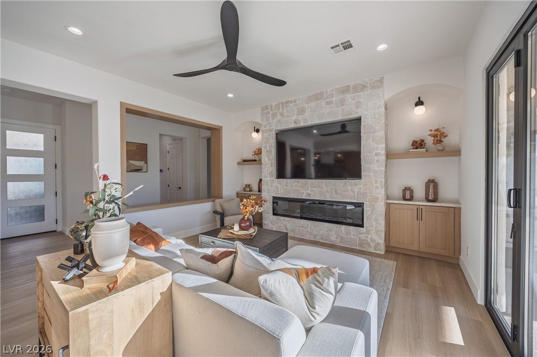 10248 Andante Court, Las Vegas, NV 89135 Living area with plenty of natural light, a stone fireplace, ceiling fan, and light wood-style flooring