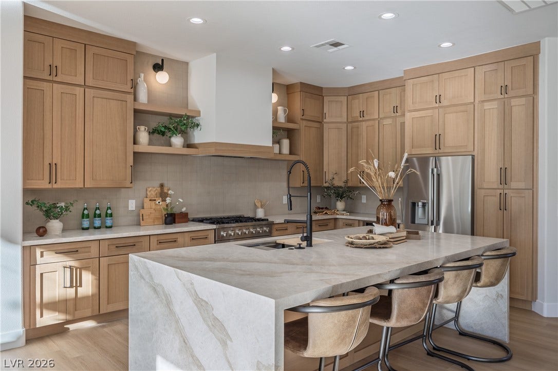 10248 Andante Court, Las Vegas, NV 89135 Kitchen with stainless steel appliances, light stone countertops, light wood-style floors, a breakfast bar, and recessed lighting