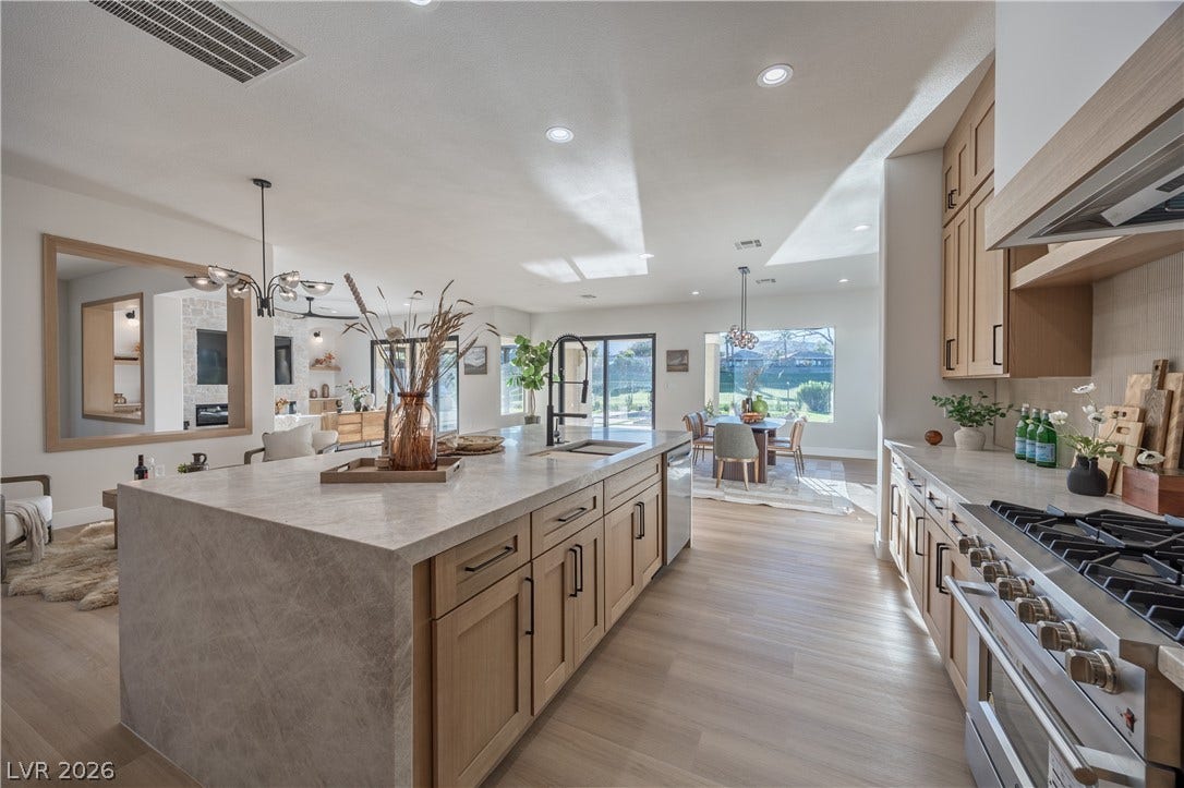 10248 Andante Court, Las Vegas, NV 89135 Kitchen featuring a chandelier, stainless steel appliances, light stone countertops, light wood-style floors, and a large island with sink