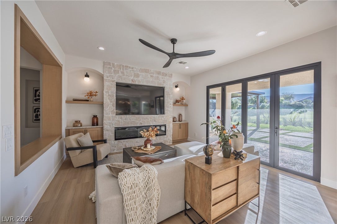 10248 Andante Court, Las Vegas, NV 89135 Living area featuring a fireplace, light wood-style floors, a ceiling fan, and french doors