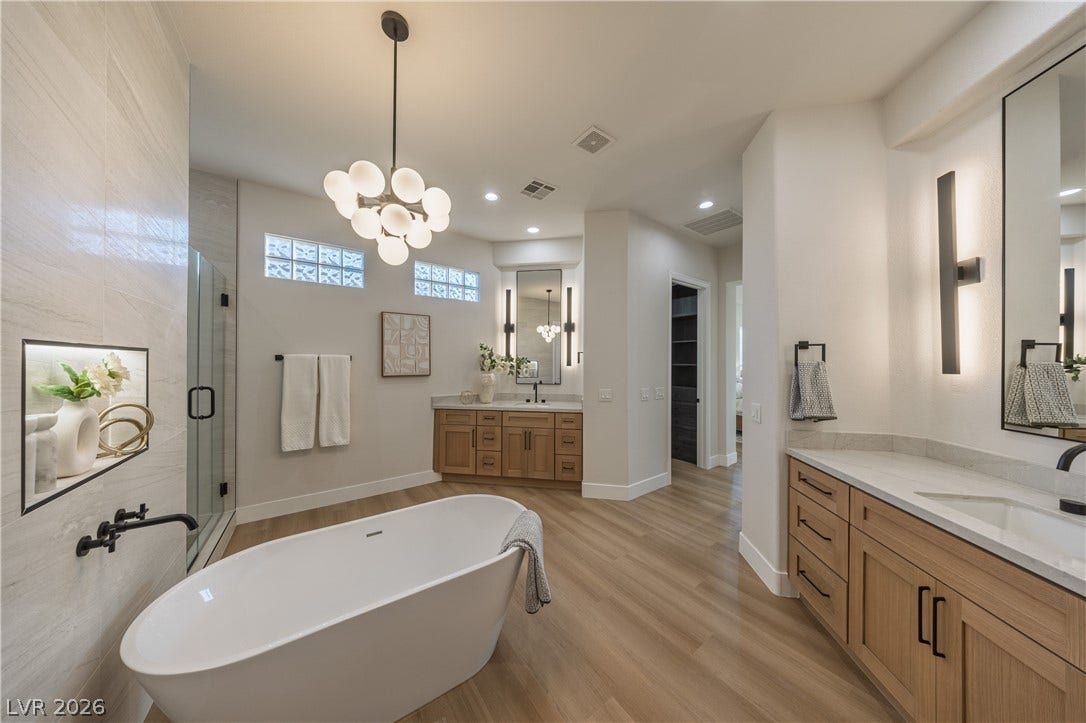 10248 Andante Court, Las Vegas, NV 89135 Full bath featuring two vanities, a shower stall, a chandelier, light wood-type flooring, and a soaking tub