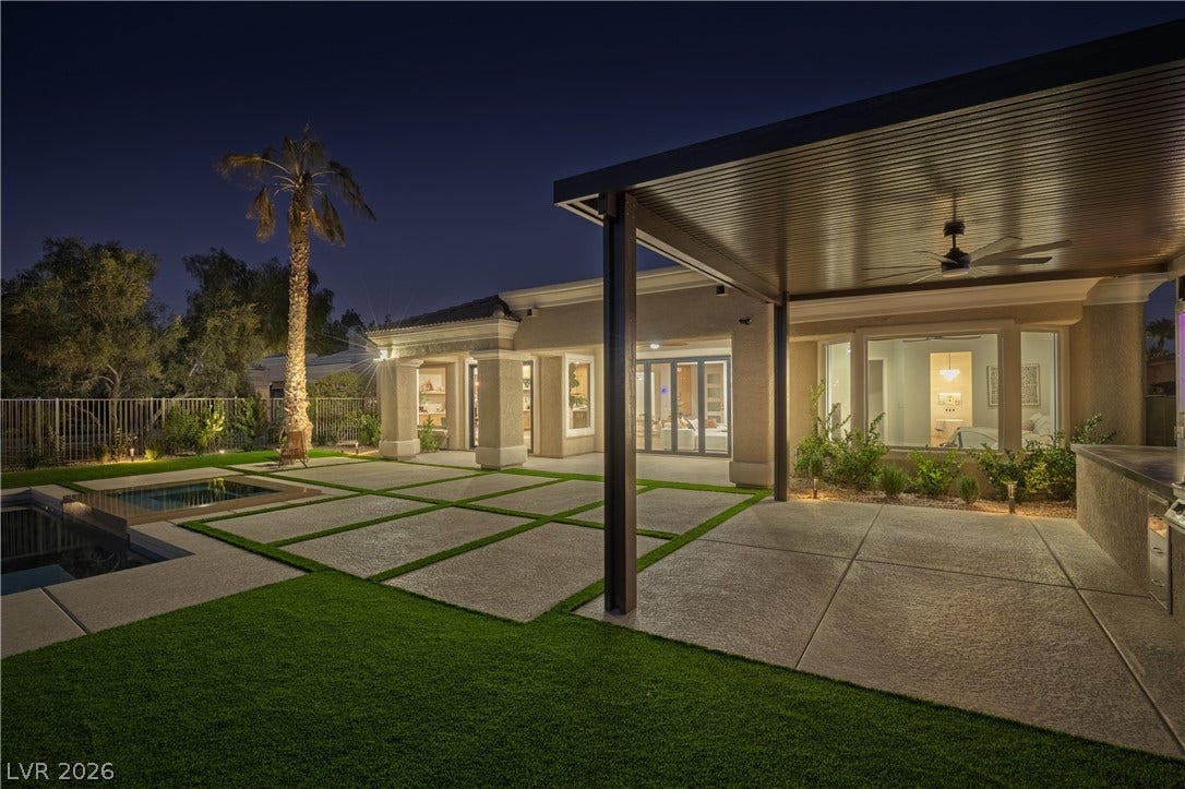 10248 Andante Court, Las Vegas, NV 89135 Back of house at night featuring a ceiling fan, a patio area, stucco siding, and a fenced backyard