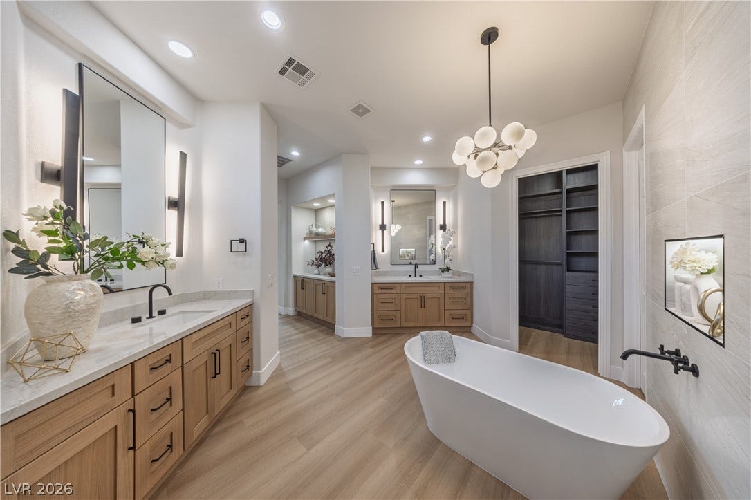 10248 Andante Court, Las Vegas, NV 89135 Bathroom featuring two vanities, light wood finished floors, a freestanding bath, and suspended lighting