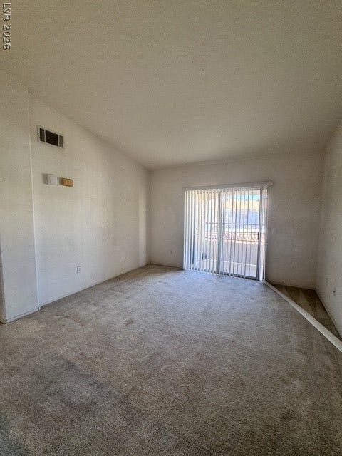 1881 W Alexander Road, #2107, North Las Vegas, NV 89032 Sliding glass doors open to a private balcony, filling the carpeted space with natural light.