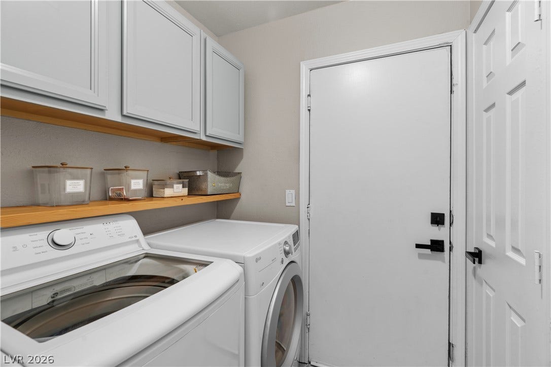 4927 Rancho Domingo Court, North Las Vegas, NV 89031 Functional laundry setup highlights overhead cabinets and open shelving above the appliances.
