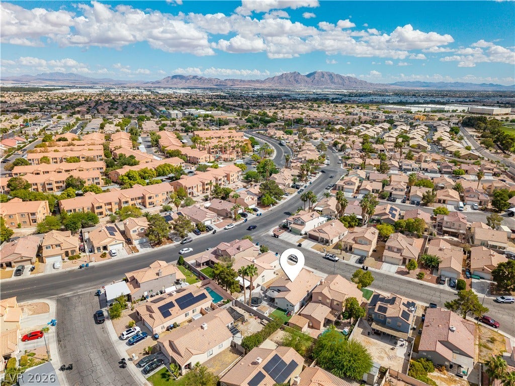 4927 Rancho Domingo Court, North Las Vegas, NV 89031 A quiet residential neighborhood unfolds beneath clear blue desert skies and distant mountain peaks.