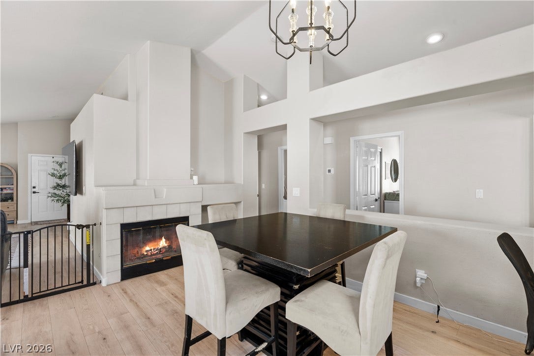 4927 Rancho Domingo Court, North Las Vegas, NV 89031 A burning fireplace accents this dining area showcasing high ceilings and hardwood flooring.