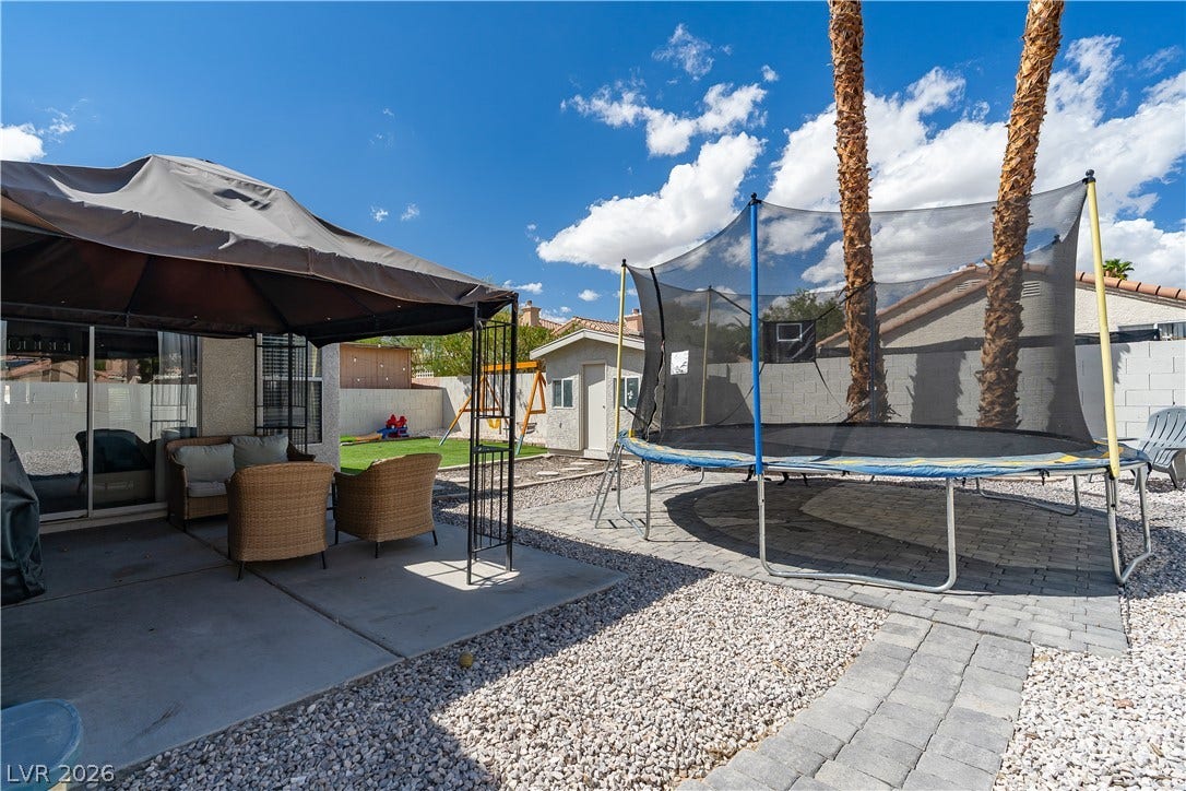4927 Rancho Domingo Court, North Las Vegas, NV 89031 An inviting backyard features a concrete patio area, a detached shed, and palm trees.