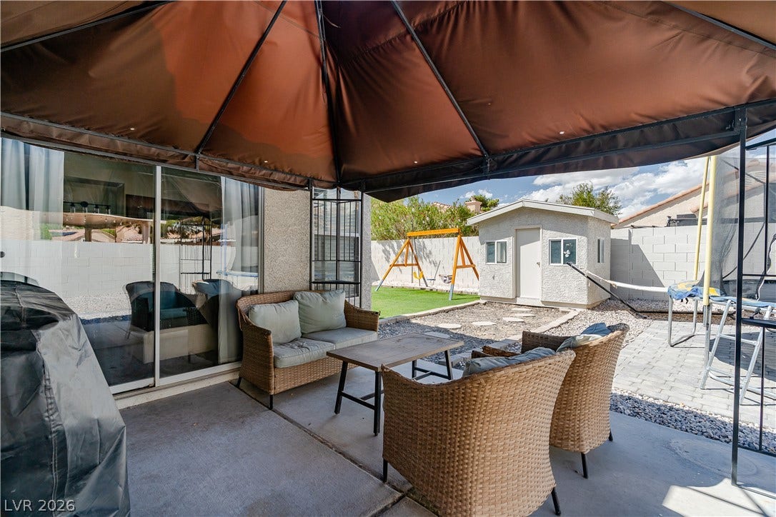 4927 Rancho Domingo Court, North Las Vegas, NV 89031 An inviting backyard patio sits adjacent to sliding doors, offering shade under a sturdy canopy.