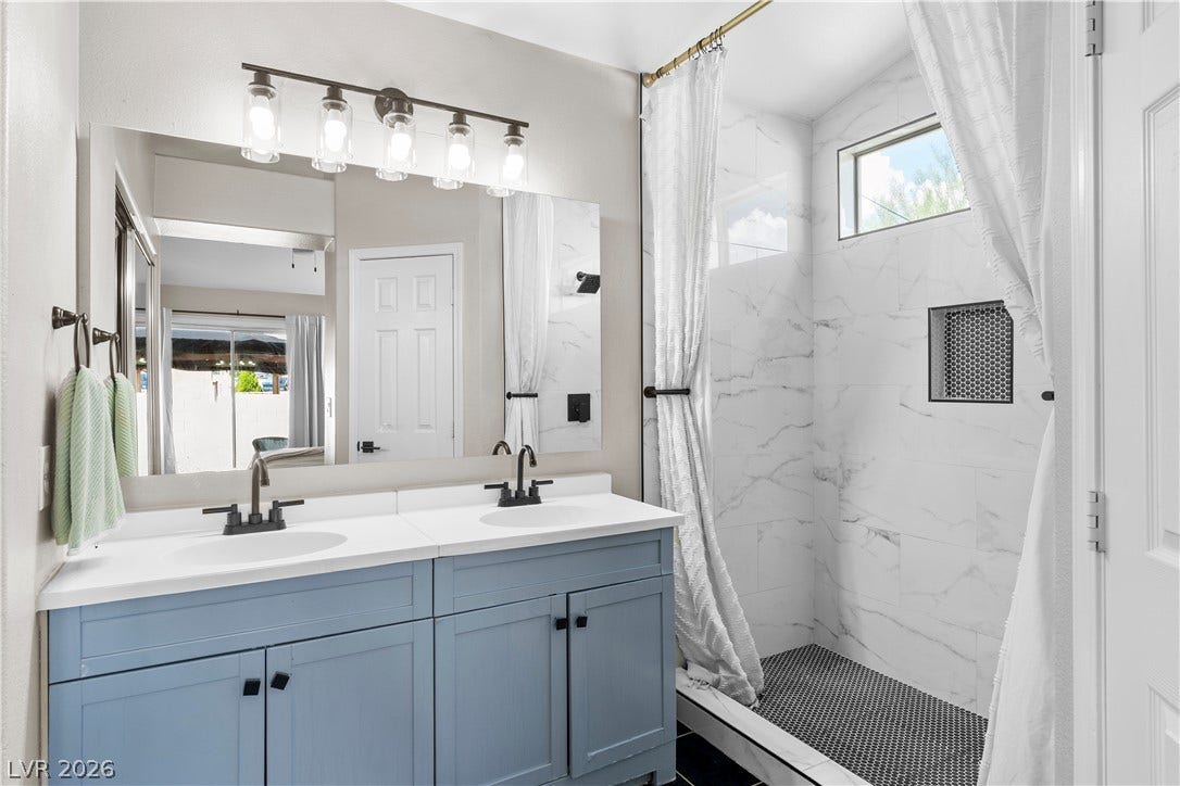 4927 Rancho Domingo Court, North Las Vegas, NV 89031 A stylish vanity paired with a modern walk-in tile shower defines this beautifully renovated bathroom.