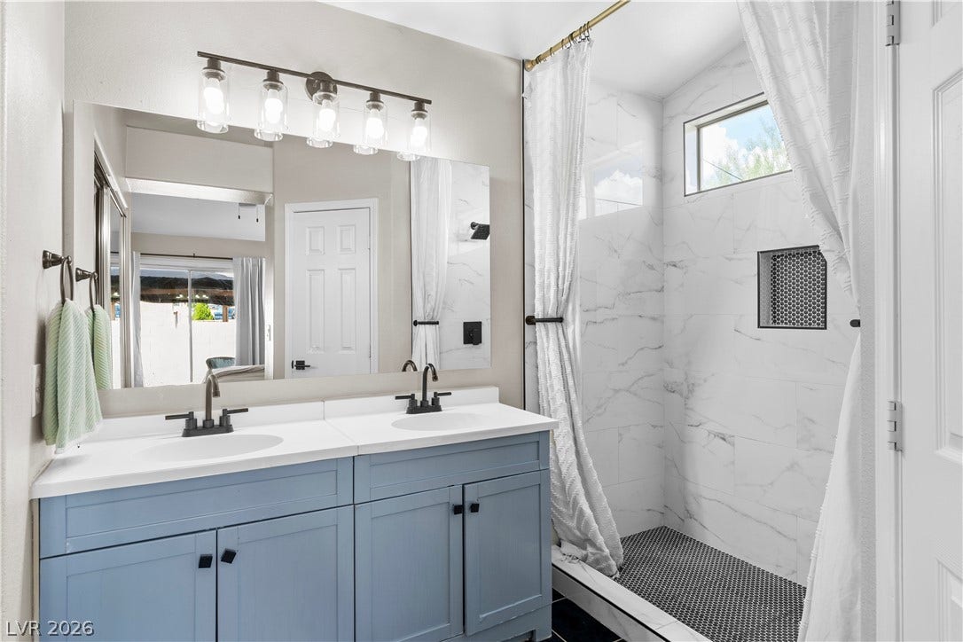 4927 Rancho Domingo Court, North Las Vegas, NV 89031 Clean lines and dual sinks define this modern bathroom with a tiled walk-in shower.