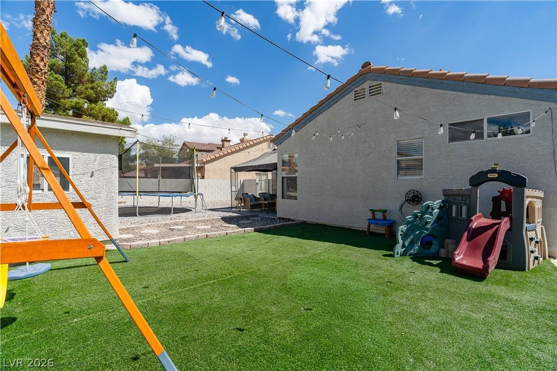 4927 Rancho Domingo Court, North Las Vegas, NV 89031 An inviting backyard features low-maintenance synthetic turf and tile roof architectural details under sunny skies.