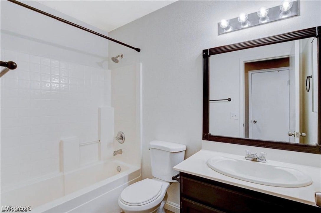 2514 Inlet Spring Avenue, North Las Vegas, NV 89031 A classic bathroom featuring a dark wood vanity and tiled tub surround.
