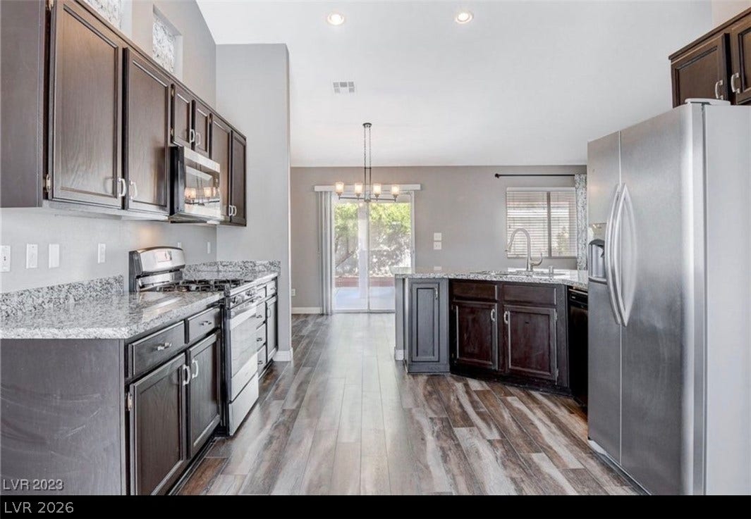 2514 Inlet Spring Avenue, North Las Vegas, NV 89031 Gleaming wood flooring complements dark cabinetry and granite countertops in this open culinary space.