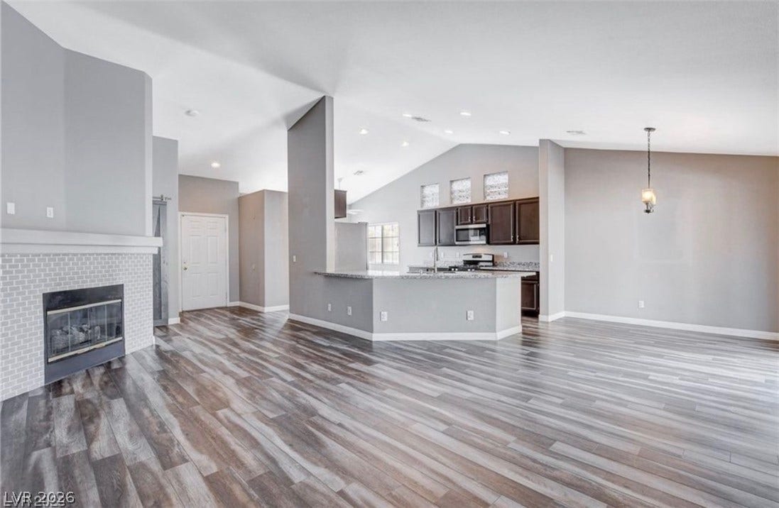 2514 Inlet Spring Avenue, North Las Vegas, NV 89031 Warm wood-look flooring and a cozy fireplace anchor this welcoming open-concept living space.