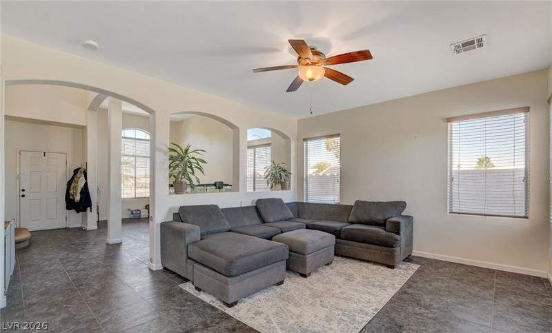 4 Goldleaf Falls Avenue, North Las Vegas, NV 89031 A spacious living area features tile flooring, high ceilings, and light-filled windows with blinds.