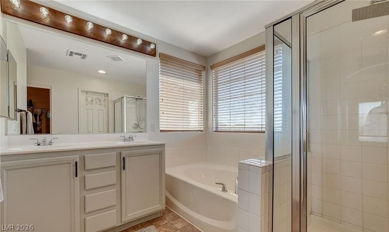 4 Goldleaf Falls Avenue, North Las Vegas, NV 89031 A spacious bathroom layout features a separate soaking tub and walk-in shower alongside double vanity sinks.