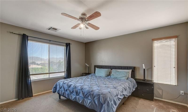 4 Goldleaf Falls Avenue, North Las Vegas, NV 89031 A spacious bedroom features neutral walls, comfortable carpeting, and windows welcoming natural light.