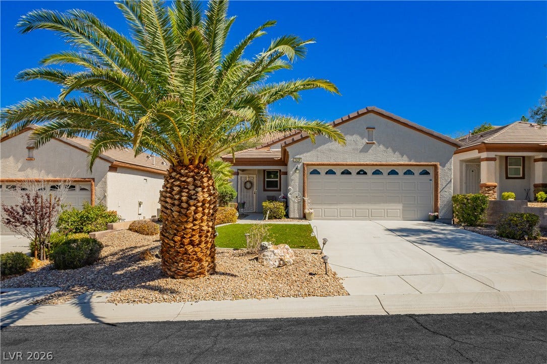 Palm trees frame a neat concrete driveway leading to a classic stucco home.
