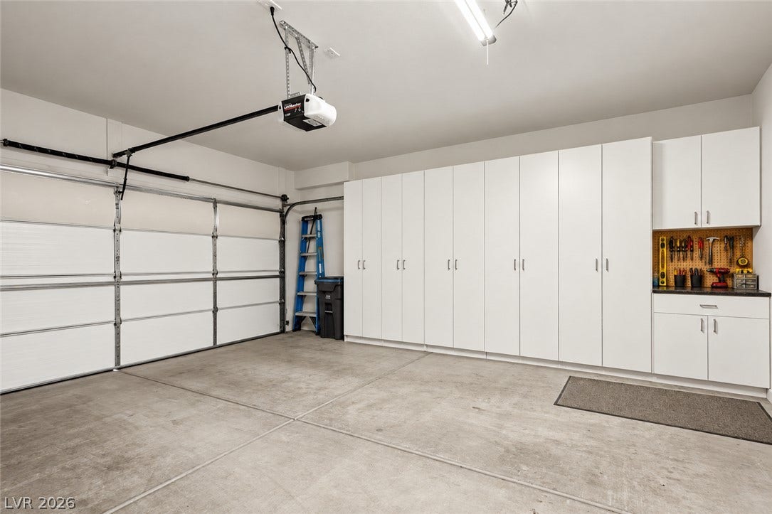 Ample built-in cabinetry and a dedicated workbench highlight this functional, concrete-floored space.