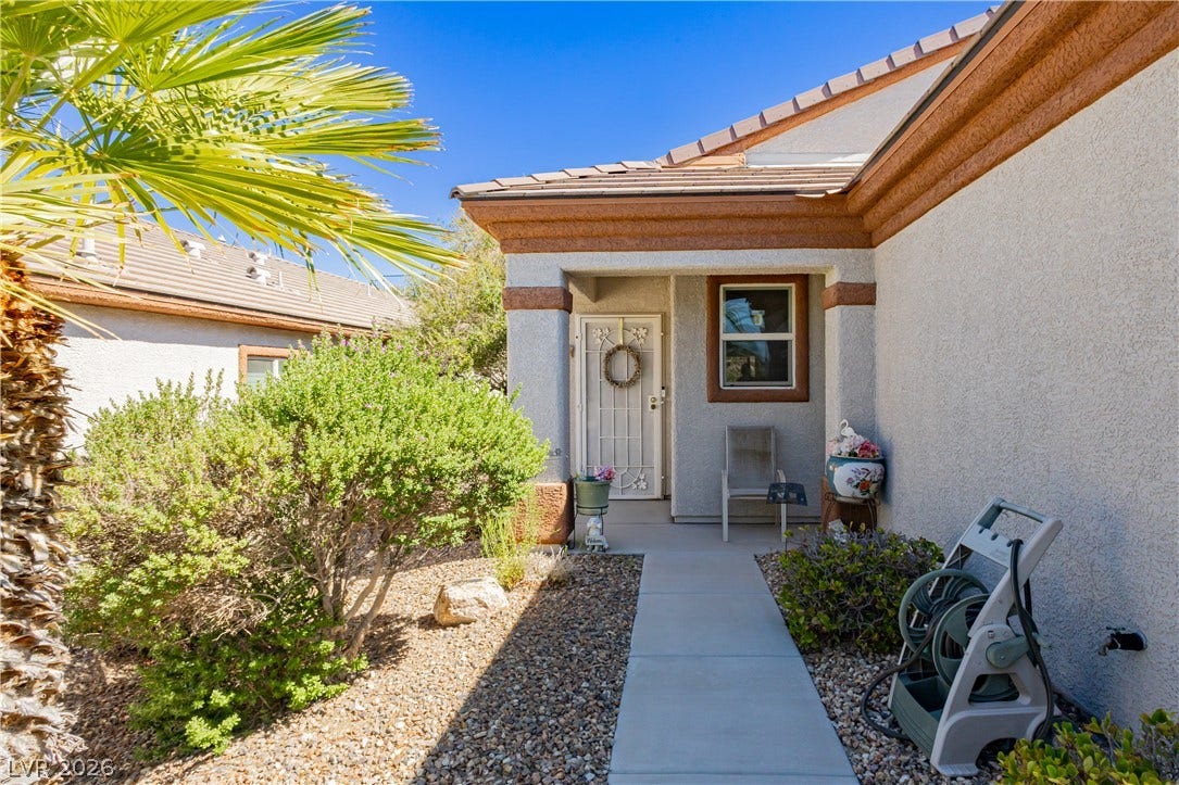 A concrete walkway leads past desert plantings to a welcoming, covered entry porch.