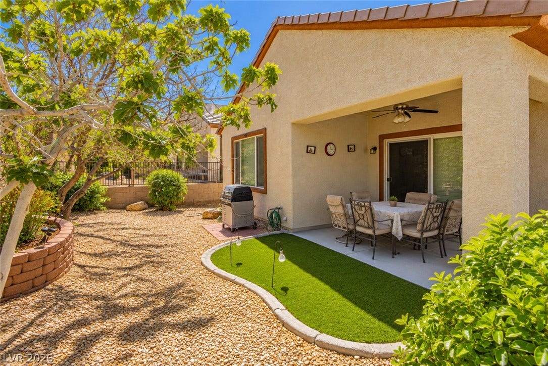 A sheltered back patio opens to a desert-landscaped yard with mature trees.
