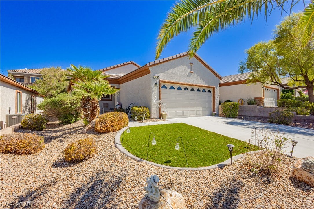 Manicured desert landscaping frames a classic stucco exterior under clear blue skies.