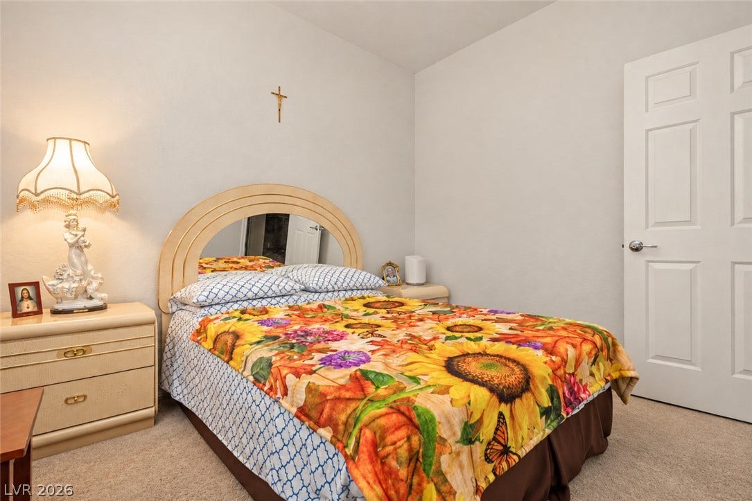 A classic six-panel door opens into this cozy carpeted bedroom.