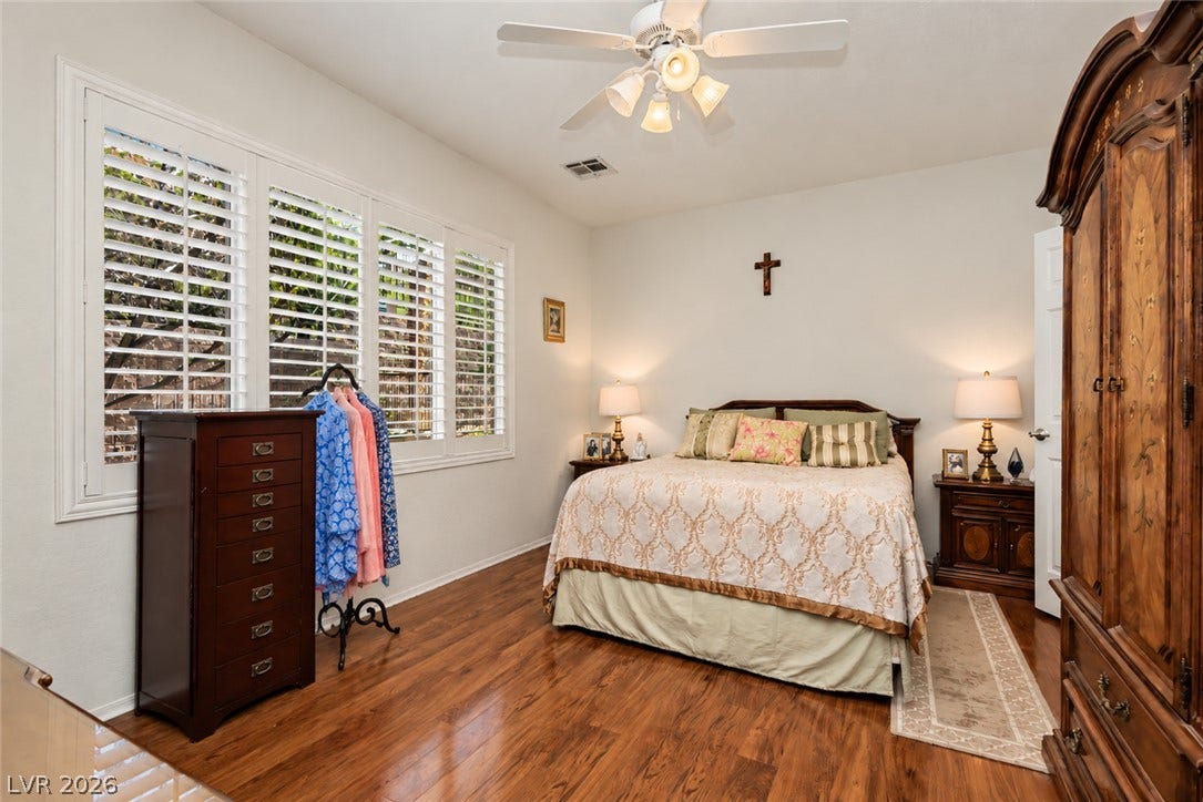Rich hardwood flooring complements the classic plantation shutters in this welcoming bedroom.