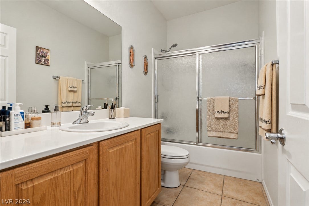 Warm wood cabinetry and durable tile flooring define this practical full bathroom.
