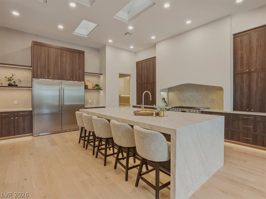3 Isleworth Drive, Henderson, NV 89052 A grand central island with seating complements this naturally illuminated chef's kitchen, featuring sleek cabinetry and light wood flooring.