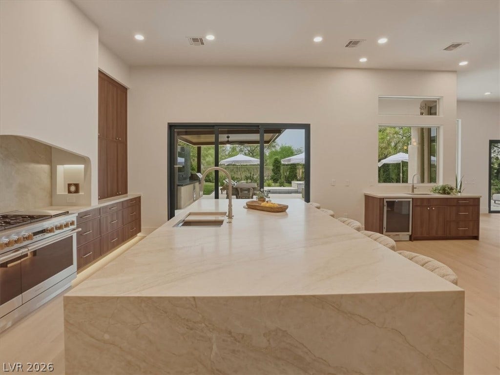 3 Isleworth Drive, Henderson, NV 89052 An open-concept kitchen features a grand stone island, high ceilings, and seamless access to outdoor living.