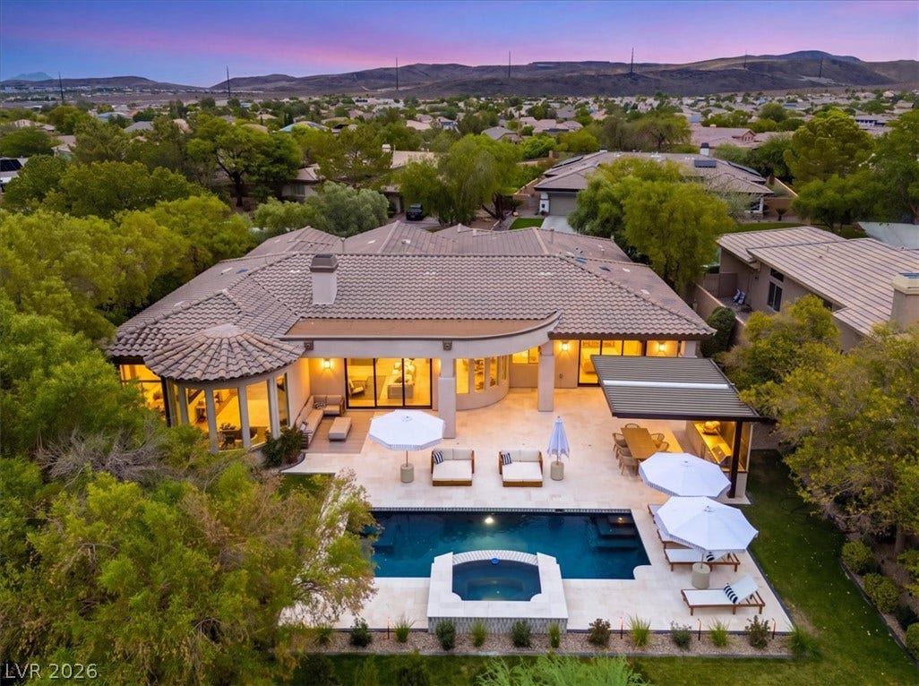 3 Isleworth Drive, Henderson, NV 89052 An aerial view showcases a grand residence with a sparkling private pool and integrated spa, framed by lush landscaping and distant mountains.