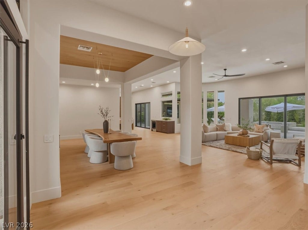 3 Isleworth Drive, Henderson, NV 89052 An open-concept design connects a naturally illuminated dining space to a comfortable living area, all adorned with gleaming wood flooring.