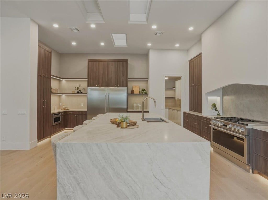 3 Isleworth Drive, Henderson, NV 89052 An inviting kitchen features a large island with sink, complemented by built-in appliances and warm wood cabinetry.