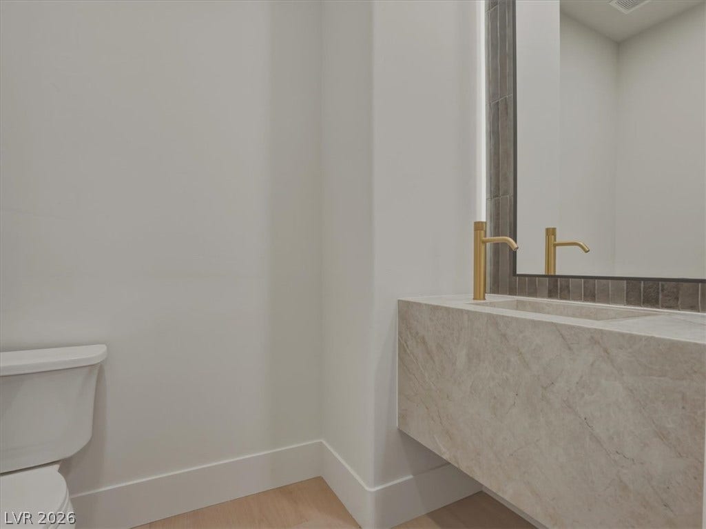 3 Isleworth Drive, Henderson, NV 89052 A refined bathroom featuring a sleek marble vanity with modern brass fixtures and a clean, minimalist design.