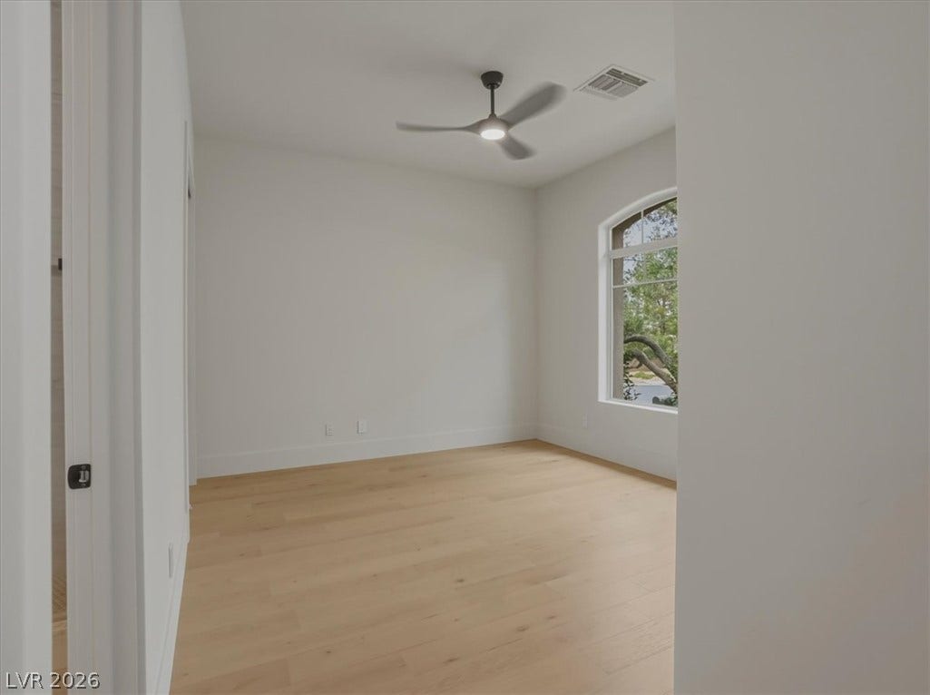 3 Isleworth Drive, Henderson, NV 89052 A well-lit bedroom features pristine hardwood flooring and a stylish ceiling fan for comfort.