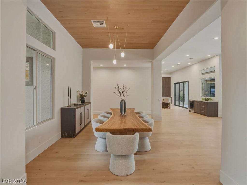 3 Isleworth Drive, Henderson, NV 89052 A well-lit dining area features a unique live-edge table and sleek wood flooring, offering an inviting atmosphere.