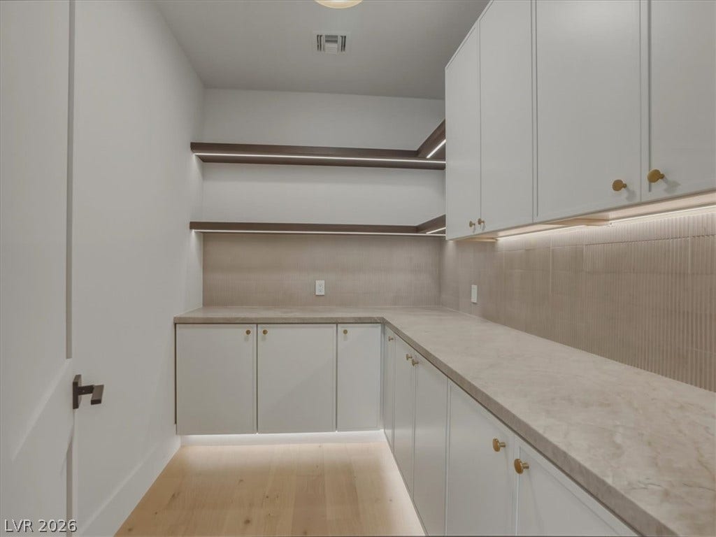 3 Isleworth Drive, Henderson, NV 89052 Functional pantry space features integrated lighting, open shelving, and extensive counter space for culinary organization.