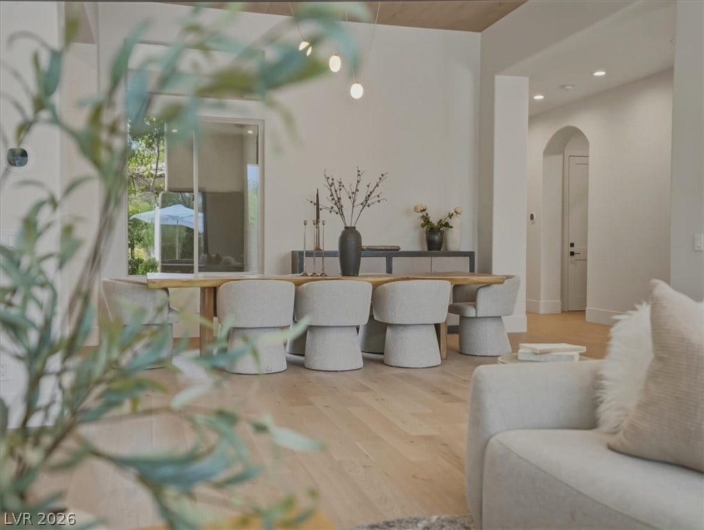 3 Isleworth Drive, Henderson, NV 89052 Blonde hardwood floors flow through this dining area, featuring a long table with modern chairs.