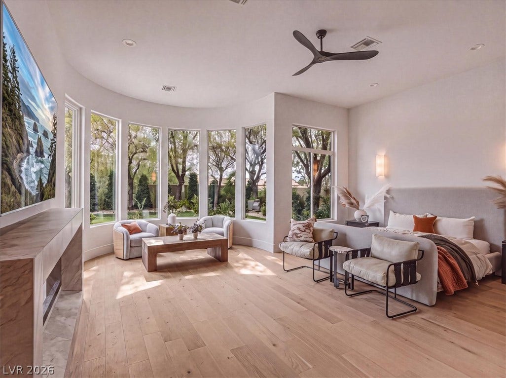 3 Isleworth Drive, Henderson, NV 89052 Natural light floods this primary bedroom, featuring a wide bay window and gleaming hardwood floors.