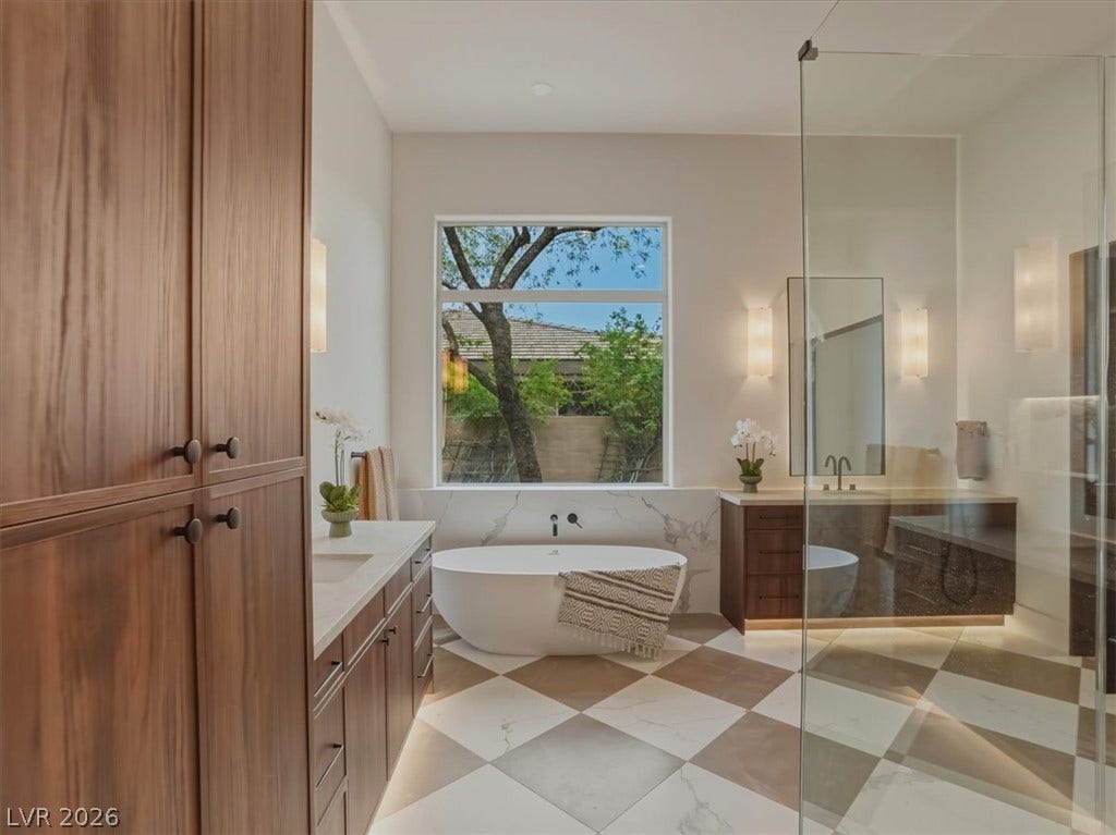 3 Isleworth Drive, Henderson, NV 89052 A well-appointed primary bathroom showcases a standalone tub, dual vanities, and a seamless glass shower.