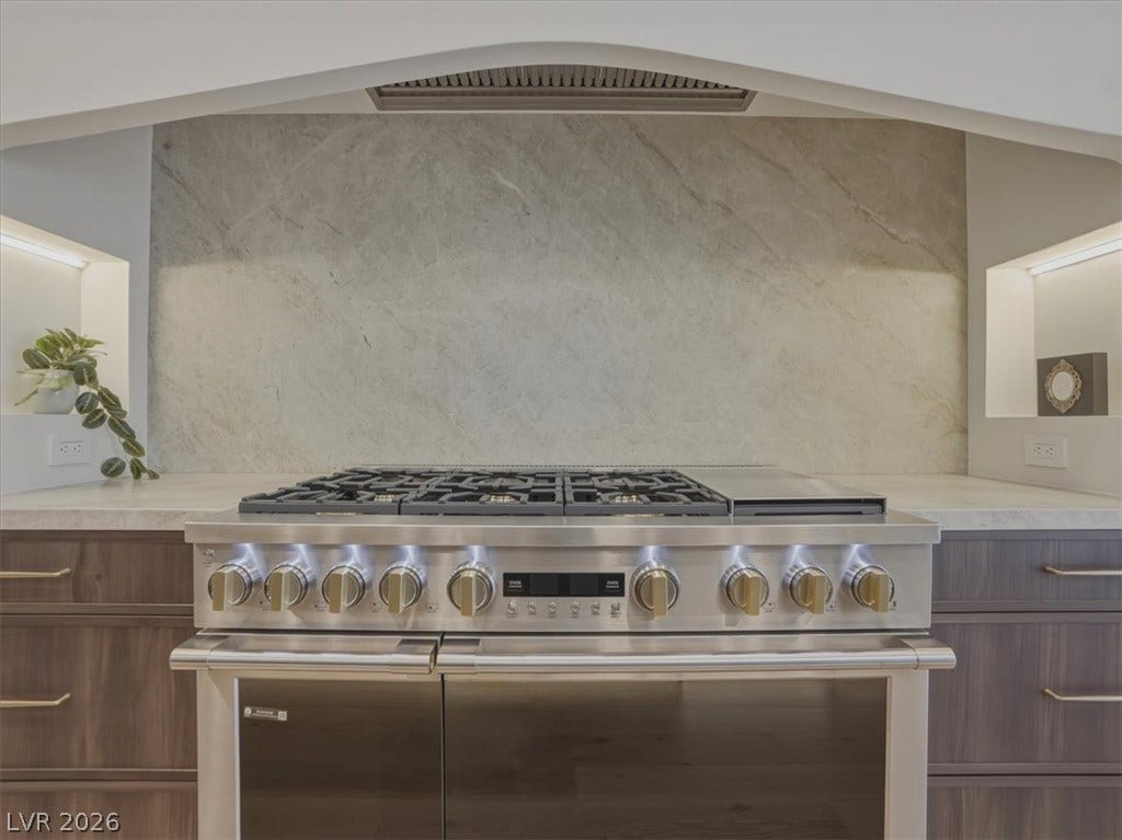 3 Isleworth Drive, Henderson, NV 89052 A well-appointed kitchen showcasing a professional-grade gas range set against a sleek stone backsplash.