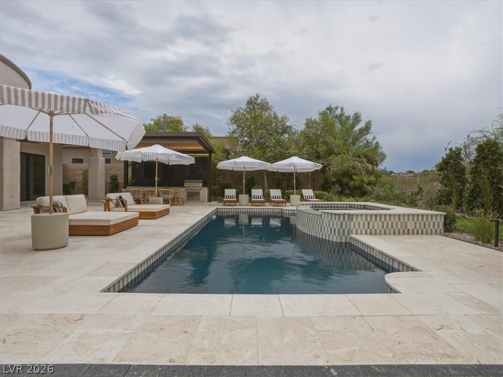 3 Isleworth Drive, Henderson, NV 89052 An inviting backyard oasis offers a sparkling pool with an integrated spa, surrounded by ample lounging space and an outdoor kitchen.