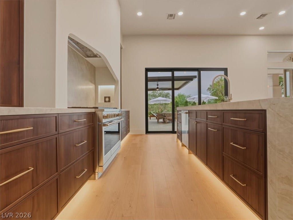 3 Isleworth Drive, Henderson, NV 89052 A well-appointed kitchen features rich wood cabinetry, stainless steel appliances, and a seamless flow to the outdoor living area.
