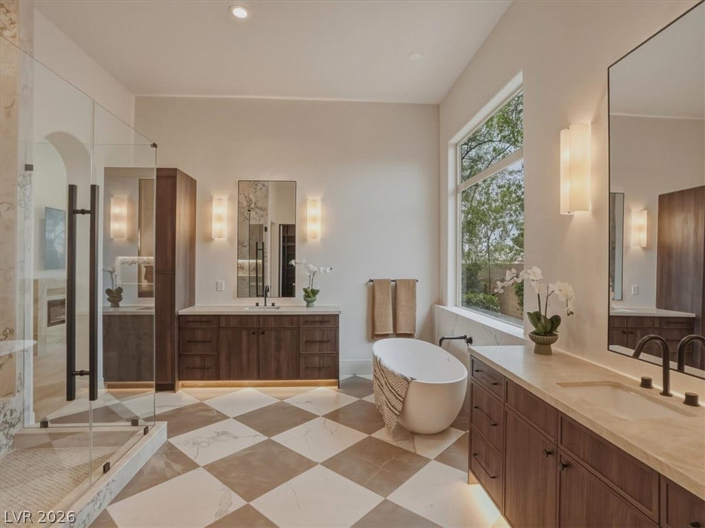 3 Isleworth Drive, Henderson, NV 89052 A lavish primary bathroom offers a spacious walk-in shower and a free-standing tub, creating a private oasis.