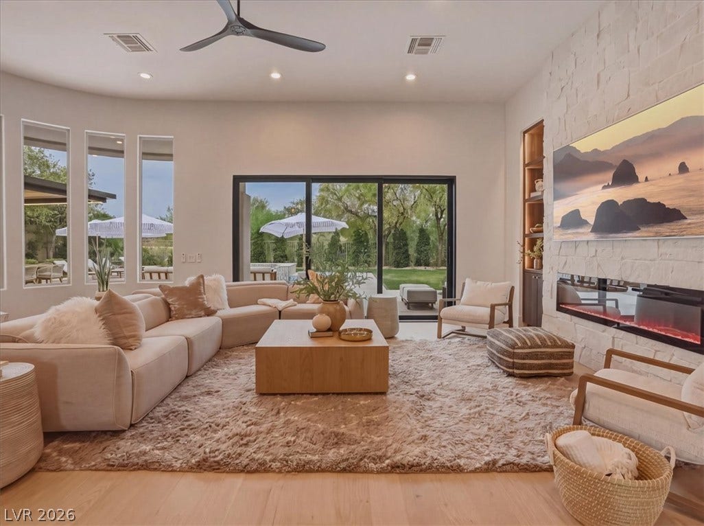 3 Isleworth Drive, Henderson, NV 89052 Natural light floods this living space, featuring high ceilings, hardwood flooring, and a modern fireplace.