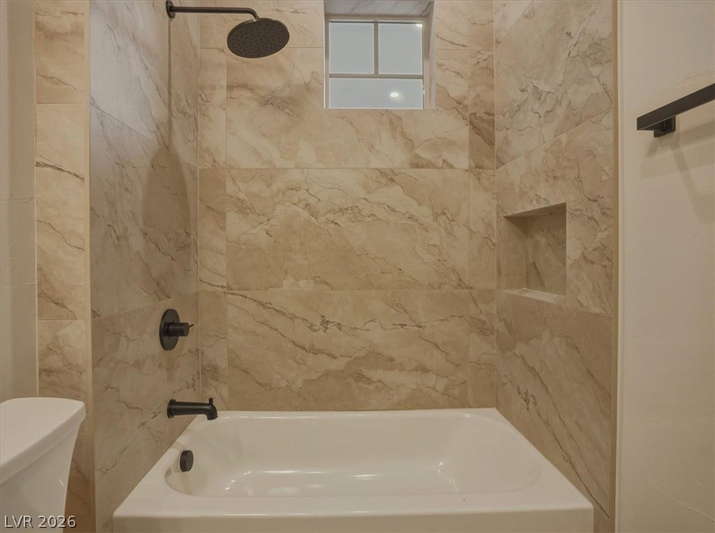 3 Isleworth Drive, Henderson, NV 89052 Marble-look tile envelops this contemporary tub and shower, featuring an integrated shower niche and dark bronze fixtures.